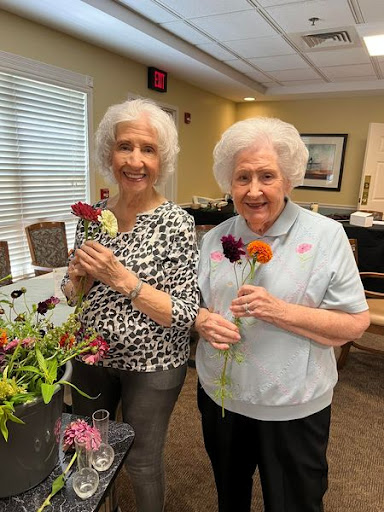 Two joyful women holding flowers, celebrating a moment together.