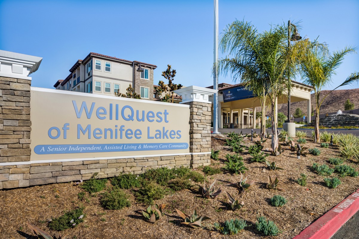 The entrance sign of WellQuest of Menifee Lakes with surrounding landscaping and a view of the building.