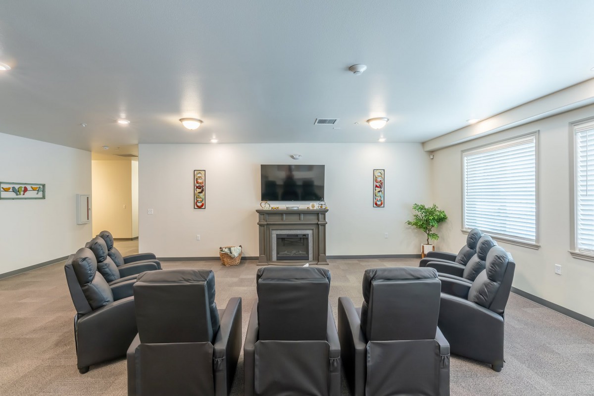 A cozy home theater room with multiple reclining chairs facing a large screen.