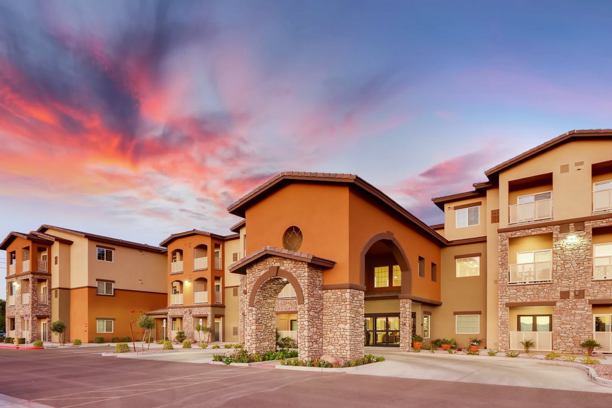 A modern residential building with stone accents under a vibrant sunset sky.