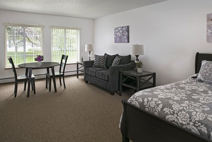 A cozy studio apartment with a sofa, dining area, and bed.
