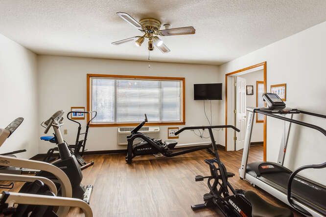 A well-lit gym room featuring various exercise machines including treadmills and stationary bikes.