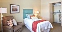 A cozy bedroom with a single bed featuring a turquoise headboard and a red blanket.