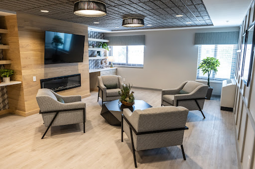 A modern living room setup featuring comfortable seating, a television, and decorative plants.