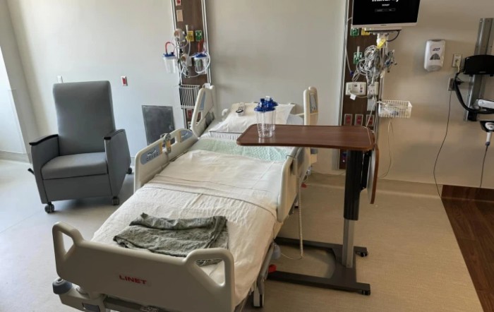 A hospital room featuring a bed, medical equipment, and a bedside table.