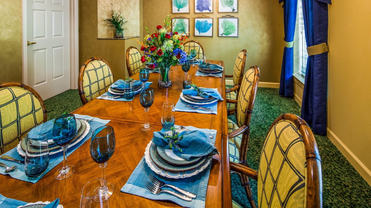 A beautifully set dining room table with blue-accented place settings and a vibrant floral centerpiece.