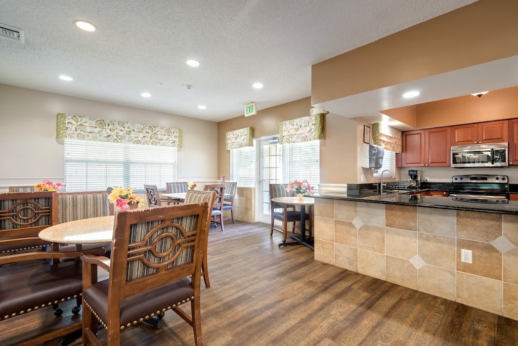 A spacious dining area connected to a kitchen, featuring wooden floors and ample natural light.