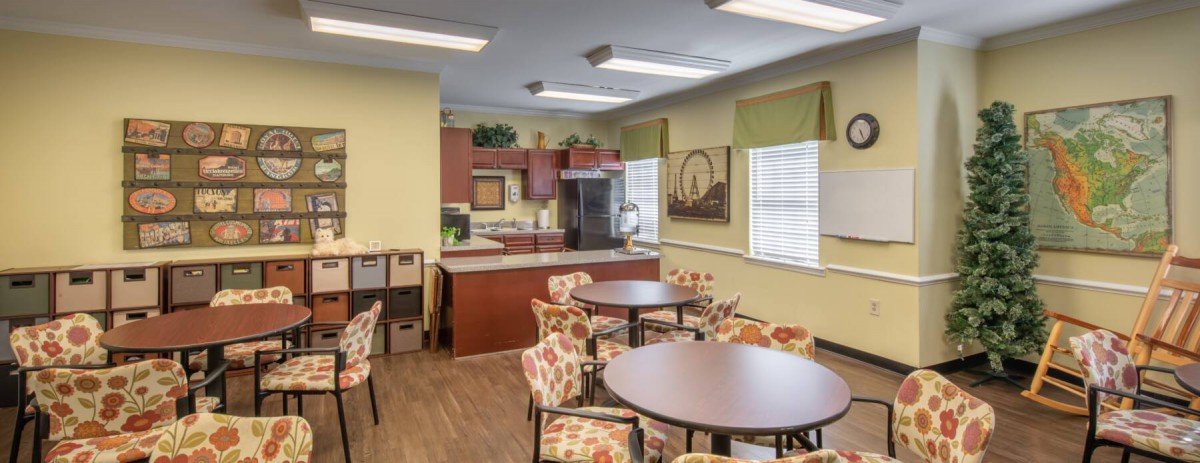 A cozy kitchen and dining area with round tables, patterned chairs, and ample natural light.