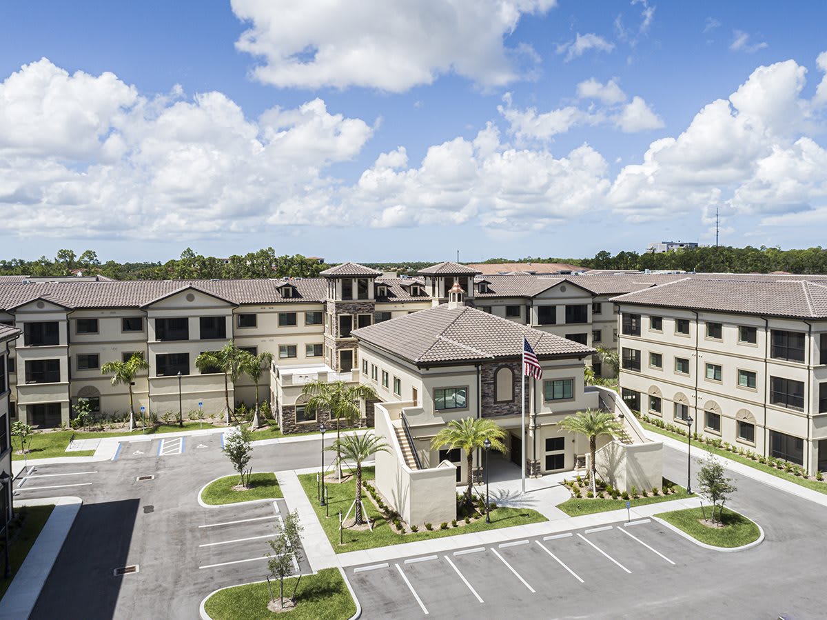 Aerial view of a residential building complex with a parking lot and a cloudy sky.