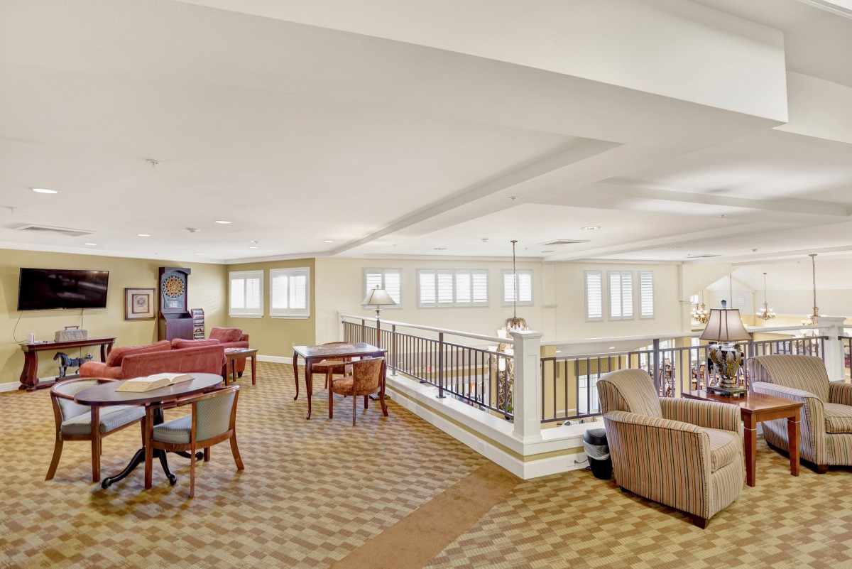 A spacious lounge area with tables, chairs, and large windows.
