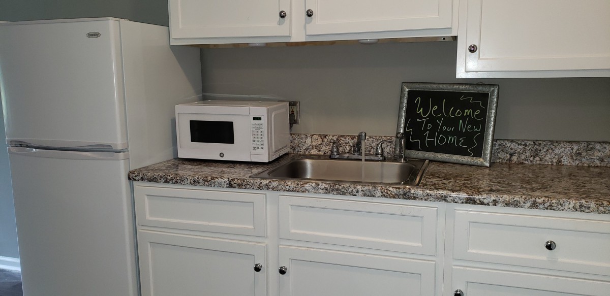 A kitchen area with a microwave and sink on a granite countertop.
