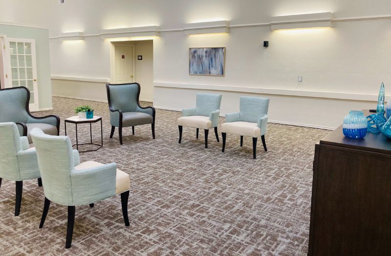 A minimalist seating area with a few chairs arranged on a patterned carpet.