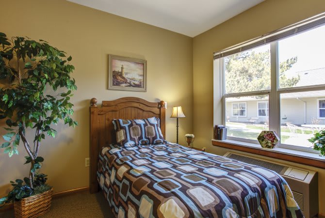 A cozy bedroom with a single bed and a large window.