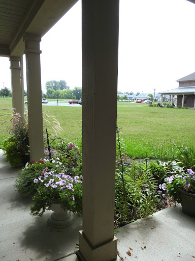 A peaceful view from the porch, showcasing a vibrant garden and expansive green lawn.
