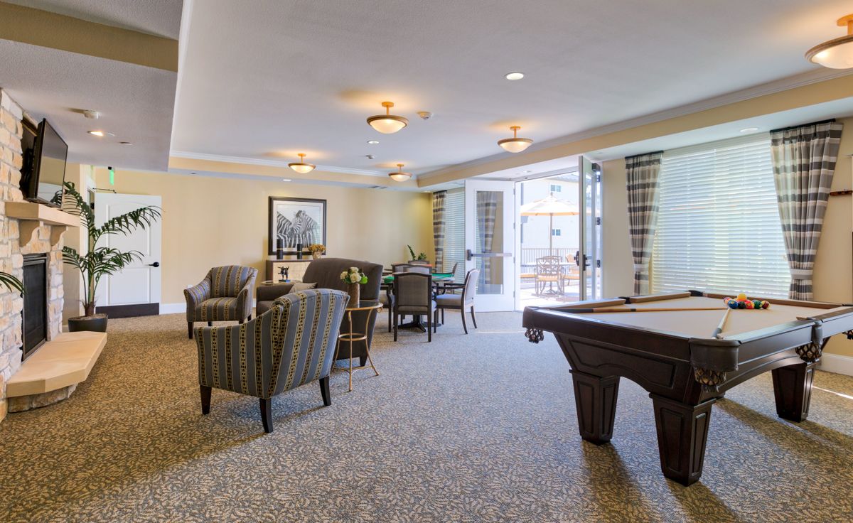 A cozy lounge area featuring a pool table and comfortable seating arrangements.