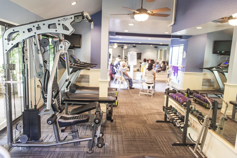 A well-equipped gym room featuring various fitness machines and weights.