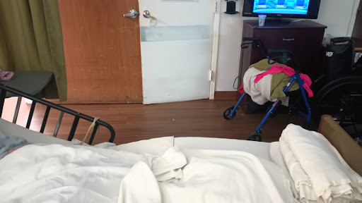 A view from a hospital room featuring a patient bed, door, and some furnishings.