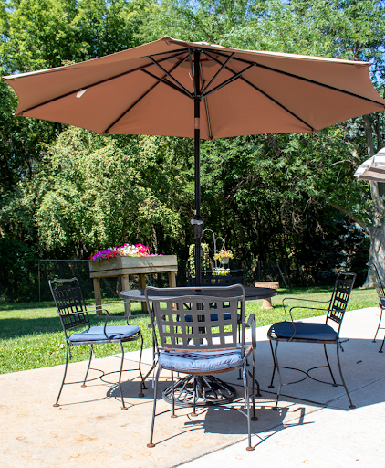 A cozy outdoor patio setup with a table, chairs, and a large umbrella for shade.
