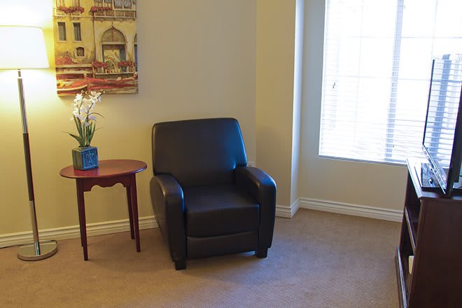 A cozy living room corner featuring a leather armchair next to a small side table and a window.