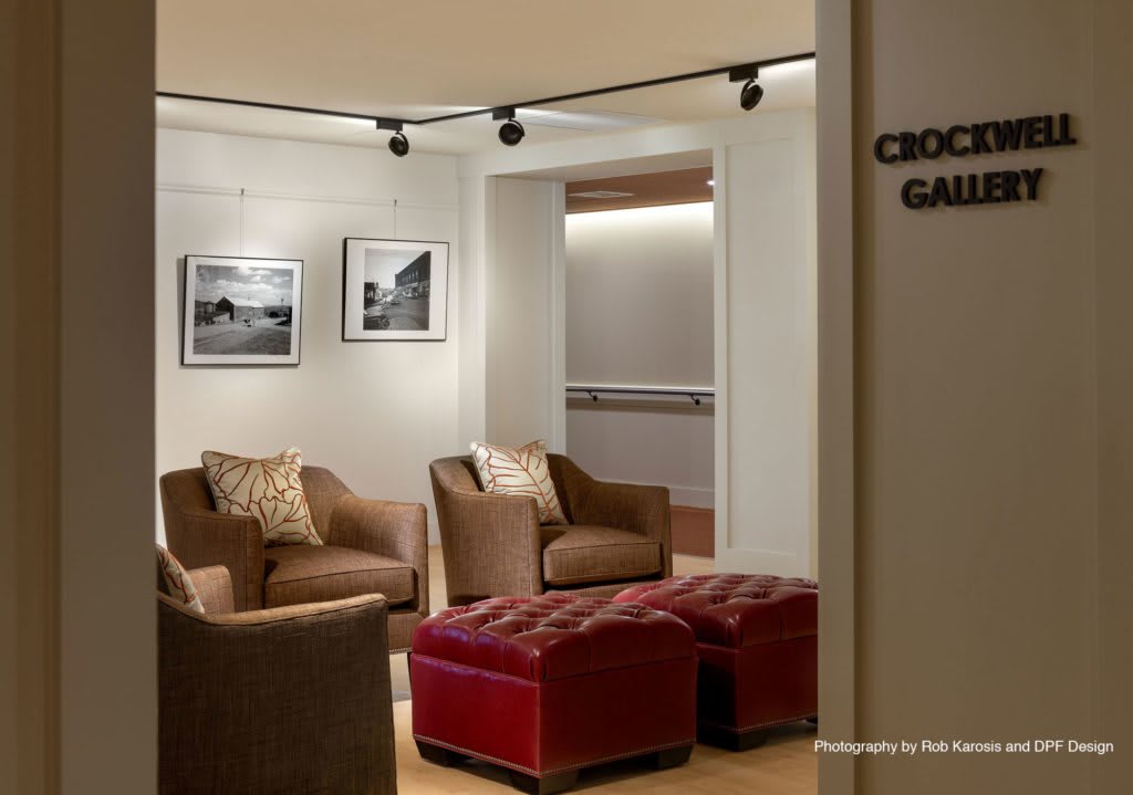 A modern gallery interior featuring cozy seating and framed photographs on the wall.