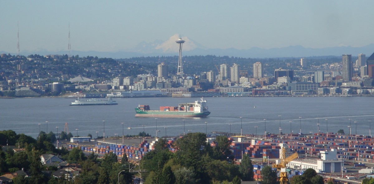 View of Seattle skyline with the Space Needle and a cargo ship in the harbor.