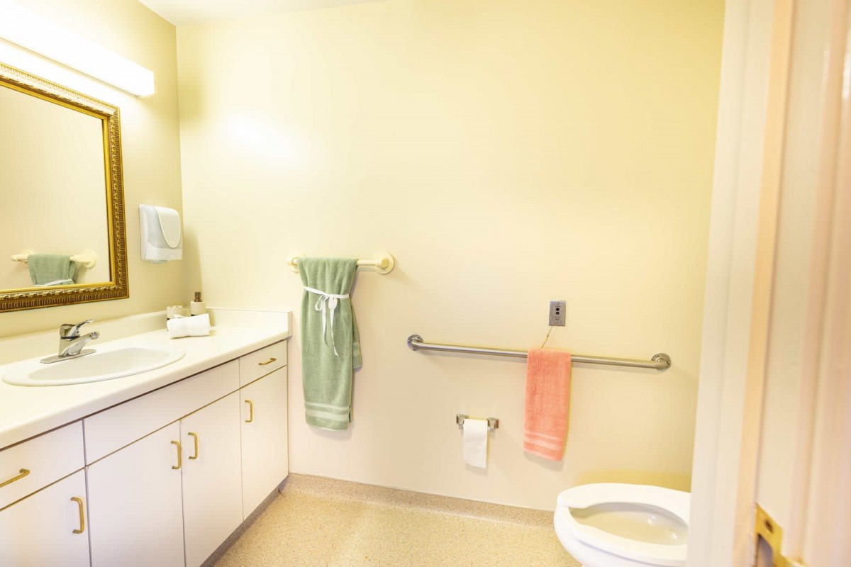 A clean and simple bathroom interior with a sink, toilet, and towels.