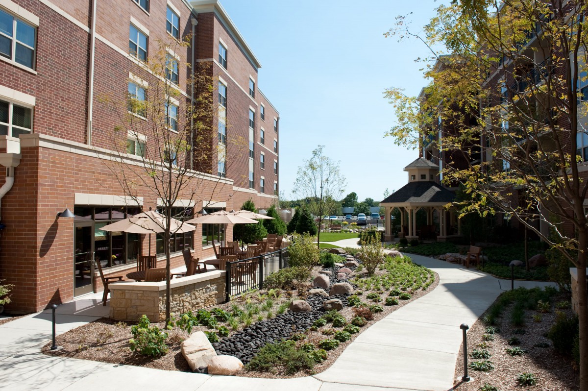 A well-landscaped outdoor area with seating next to a brick hotel building.