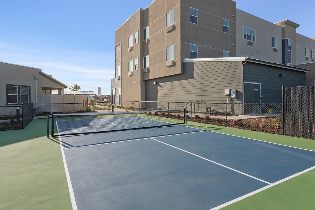 An outdoor tennis court adjacent to a modern building.