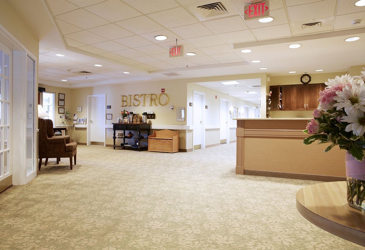 A cozy bistro with a reception area and seating in a carpeted hallway.