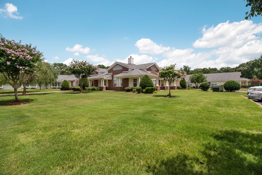 A large house with a spacious green lawn under a clear blue sky.