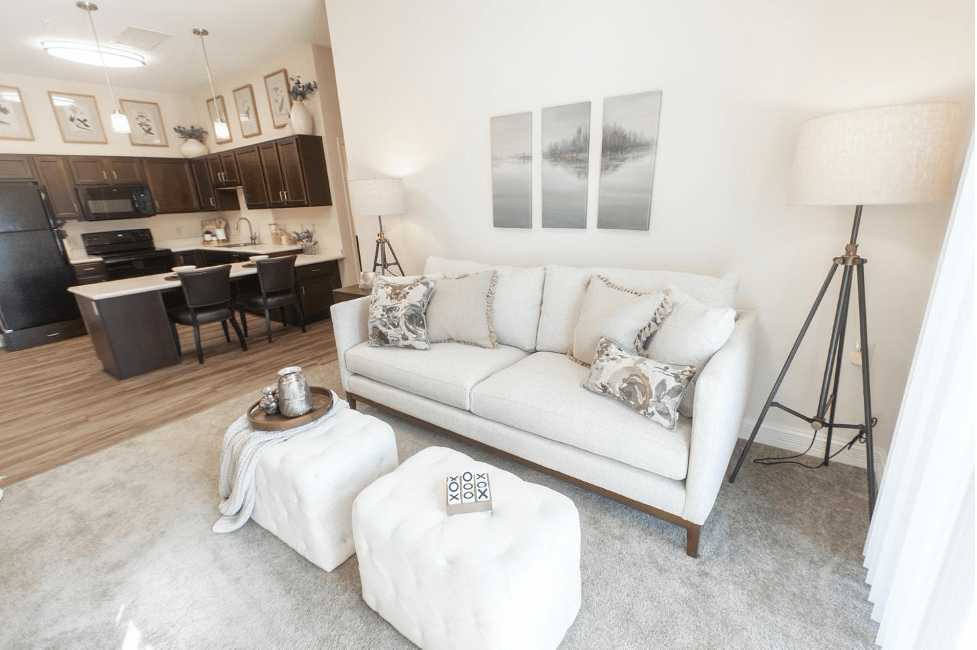 A modern and minimalist living room featuring a white sofa, decorative pillows, a small coffee table, and wall art in neutral tones.