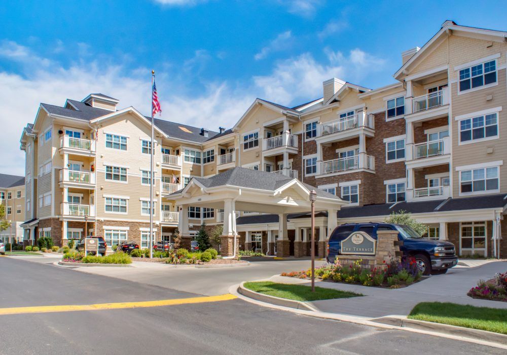 A modern residential building with balconies and well-maintained landscaping under a blue sky.