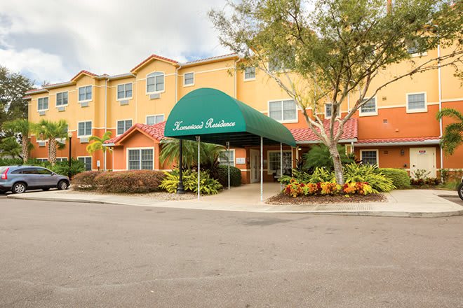 A hotel entrance with a green awning and surrounding foliage.