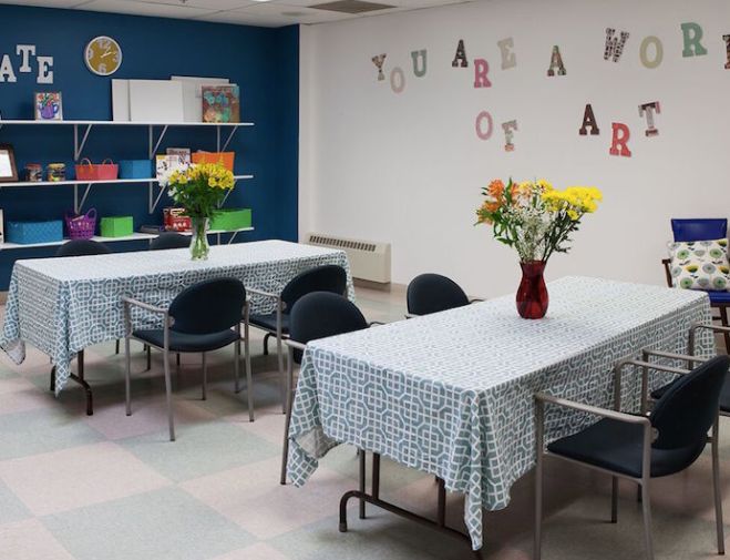 A classroom with decorated tables, chairs, and flowers arranged in vases, suggesting an art or activity space.