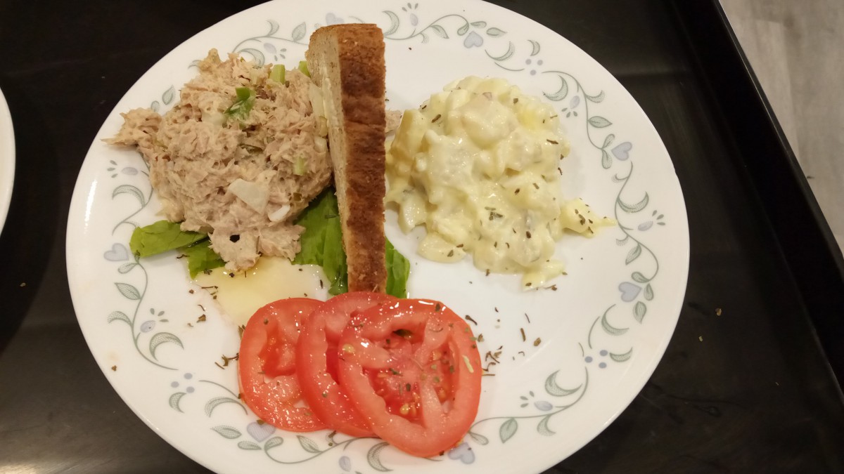 A plate with tuna salad, egg salad, toasted bread, and tomato slices.