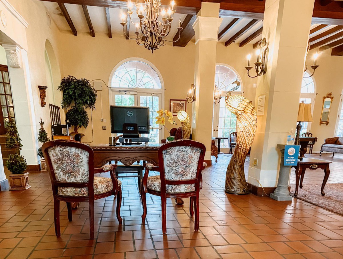 A classic living room with elegant furnishings, featuring chandeliers, wooden beams, and arched windows.