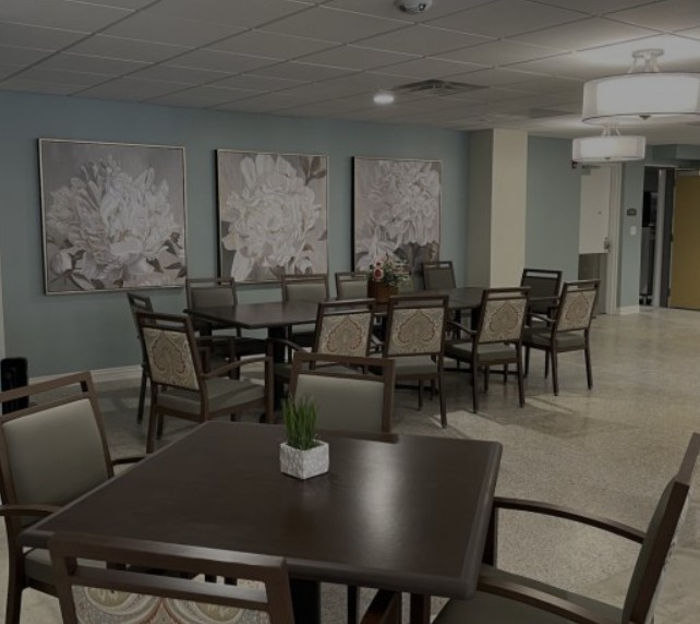 A spacious dining area with neatly arranged tables and chairs, adorned with floral artwork on the walls.