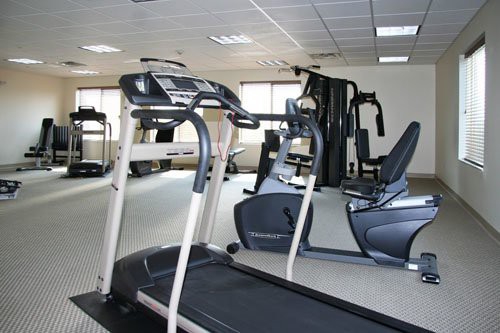 An image of a gym with various exercise equipment including a treadmill and stationary bike.
