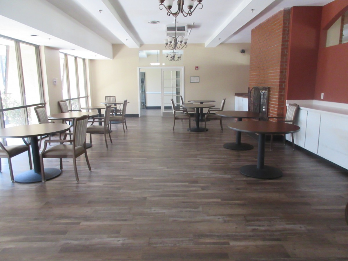 An empty dining area with wooden floors and chandelier lighting.