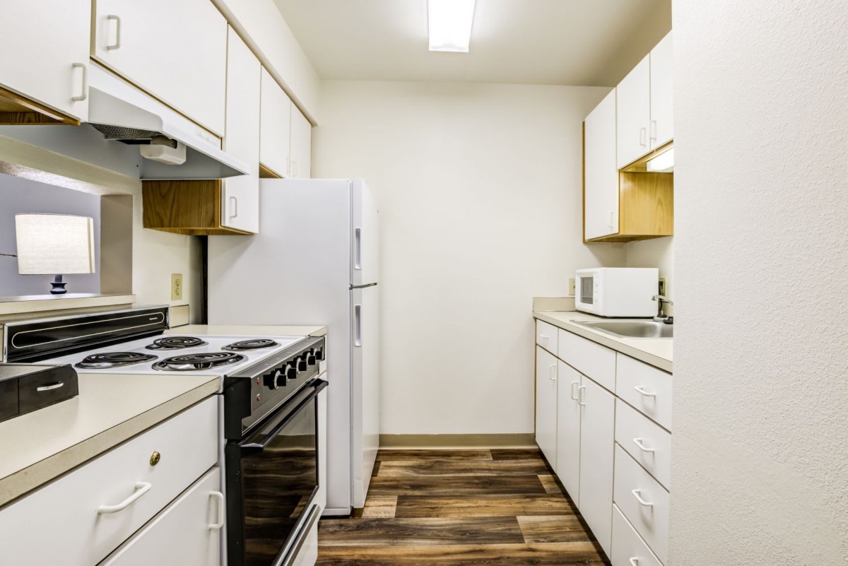 A compact modern kitchen with white cabinets and essential appliances.