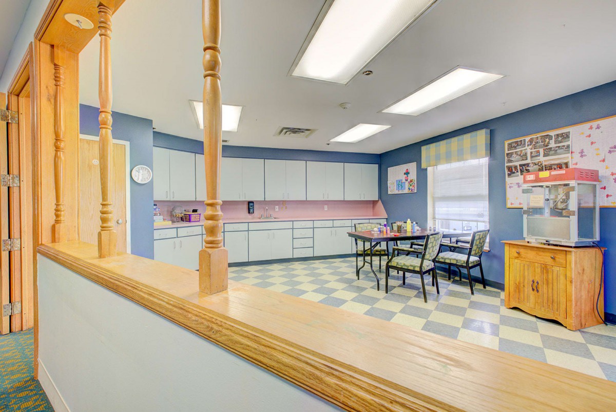 Retro-style kitchen with checkered flooring and blue walls, featuring dining table and chairs.