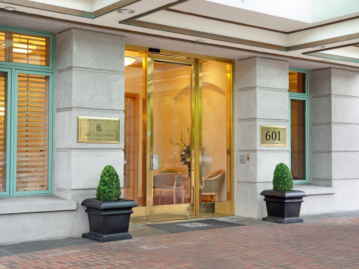 Elegant building entrance with glass doors and decorative plants.