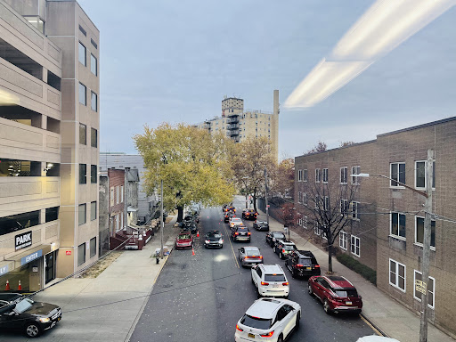A view of a bustling urban street lined with parked cars and golden autumn trees.
