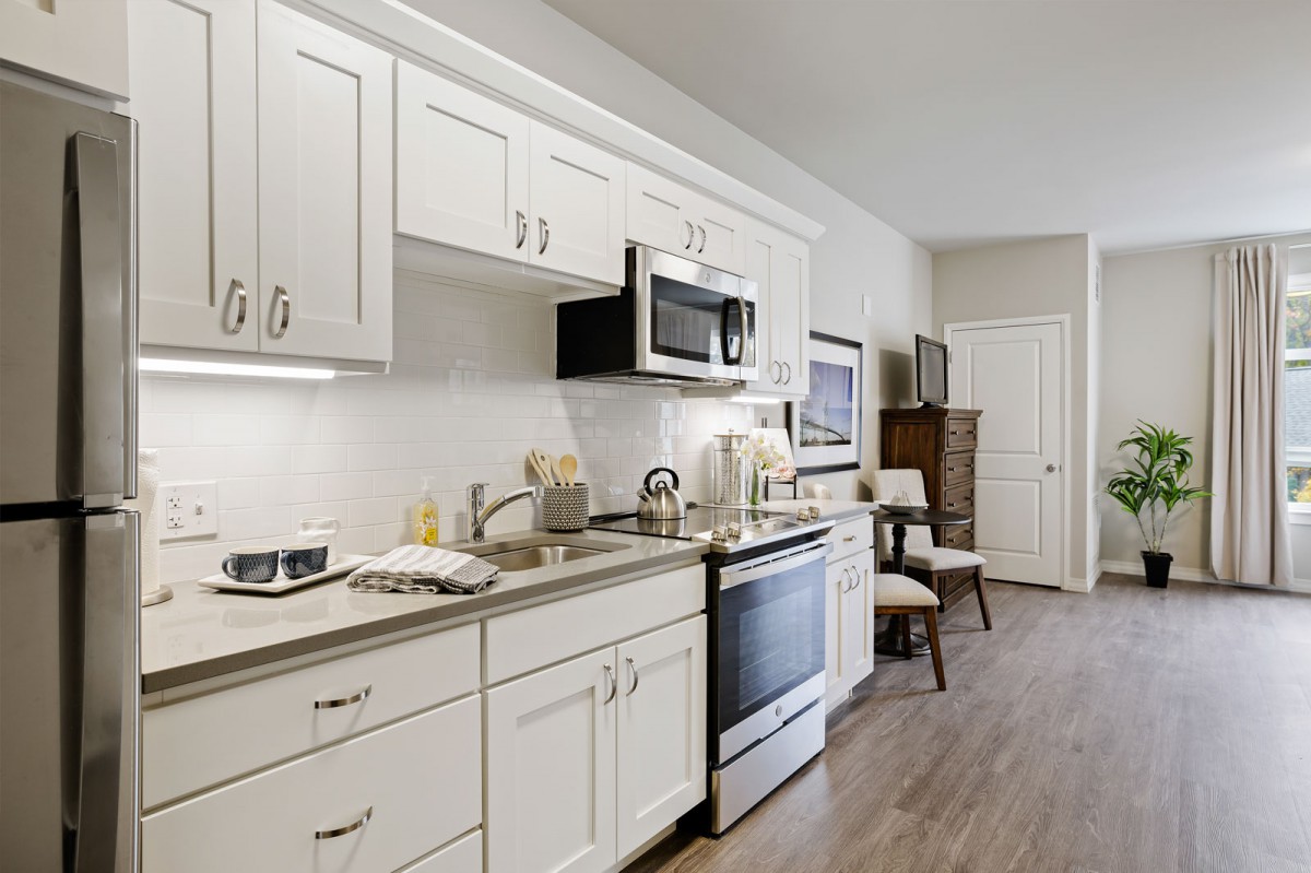 A modern kitchen with white cabinets and appliances.