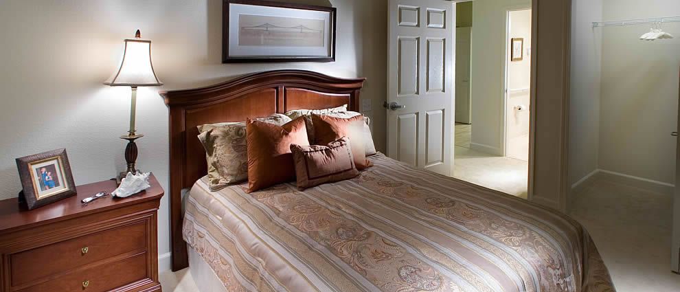 A cozy bedroom featuring a neatly made bed with multiple pillows and a wooden headboard.