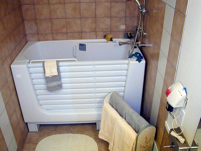 A cozy bathroom featuring a bathtub with a shower, neatly arranged towels, and tiled walls.