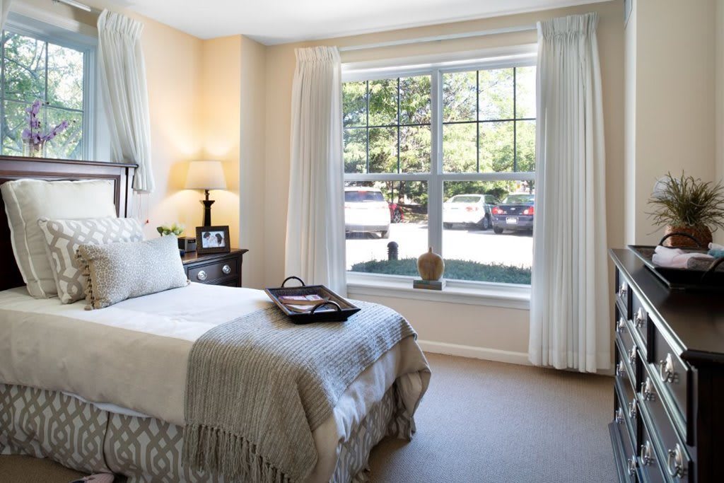 A cozy bedroom with large window and elegant decor.