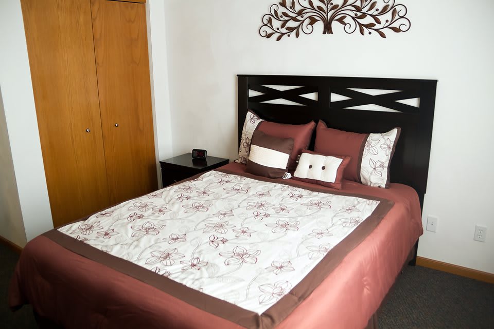 A neatly arranged bedroom with a decorative headboard and floral quilt.