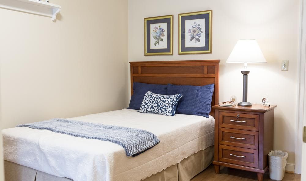 A cozy bedroom with a neatly made bed, nightstand, and decorative wall art.