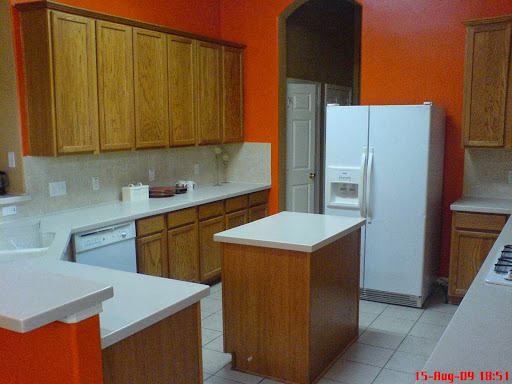 A modern kitchen featuring wooden cabinets and an orange accent wall.